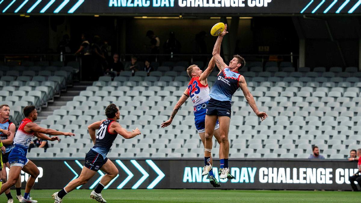 Two football players leap for the ball during a game.