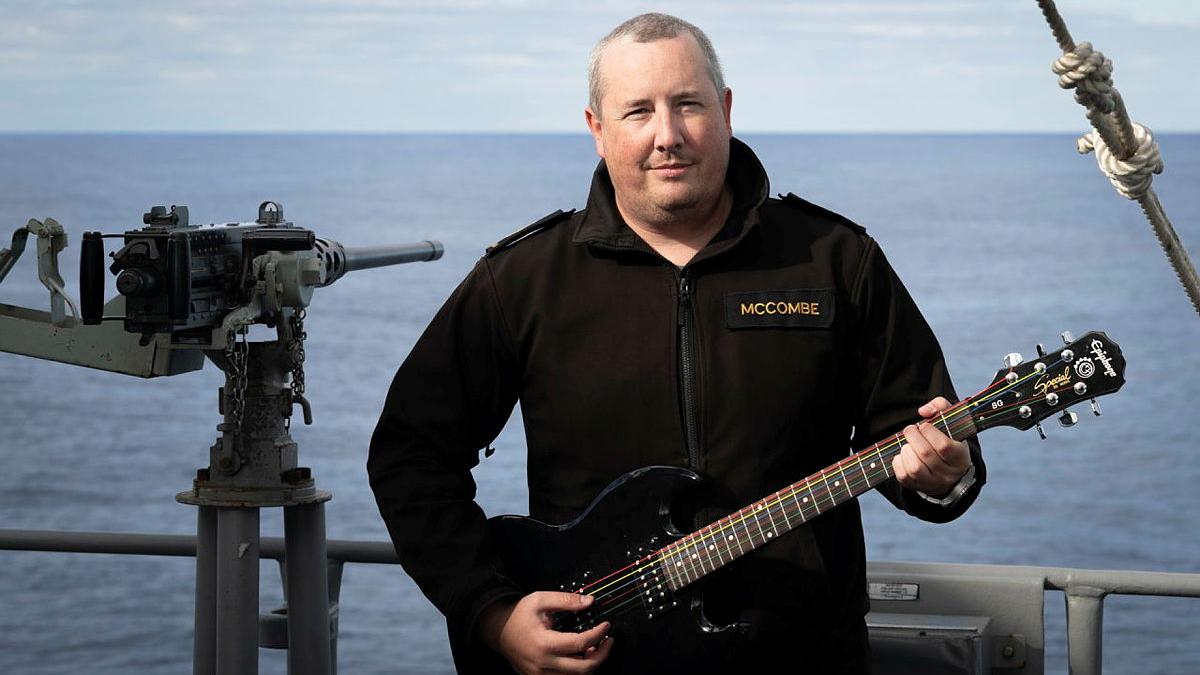Chief Petty Officer Boatswain William McCombe with his electric guitar on the upper deck of HMAS Ballarat while at sea.