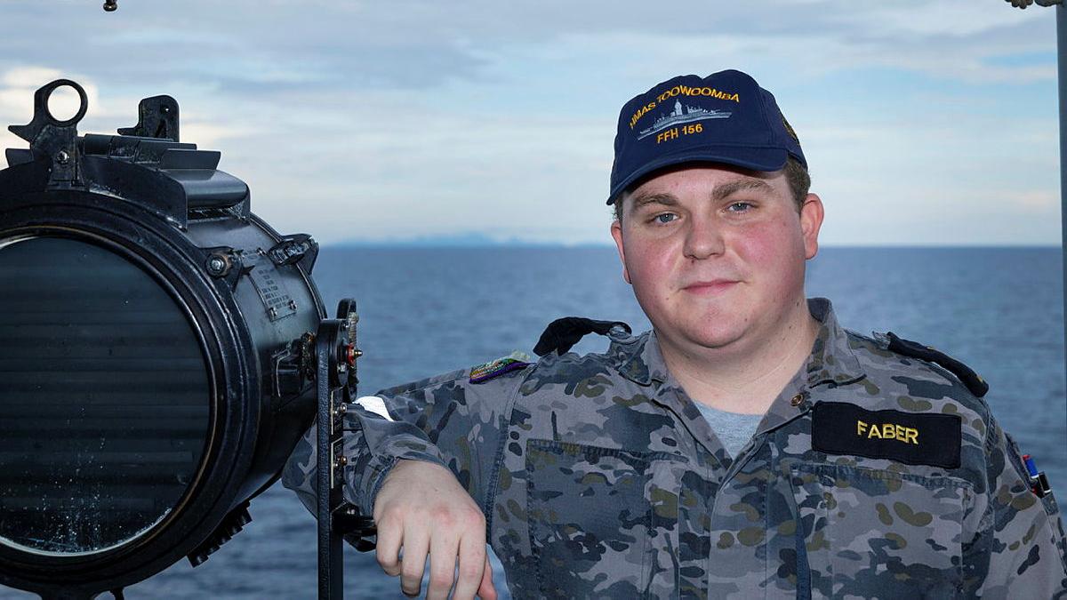 A man stands on a ship at sea.