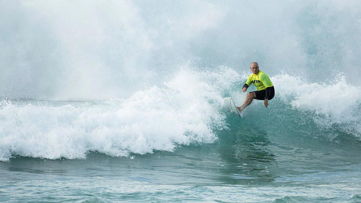 A Navy officer leans into a surf move on a breaking wave.