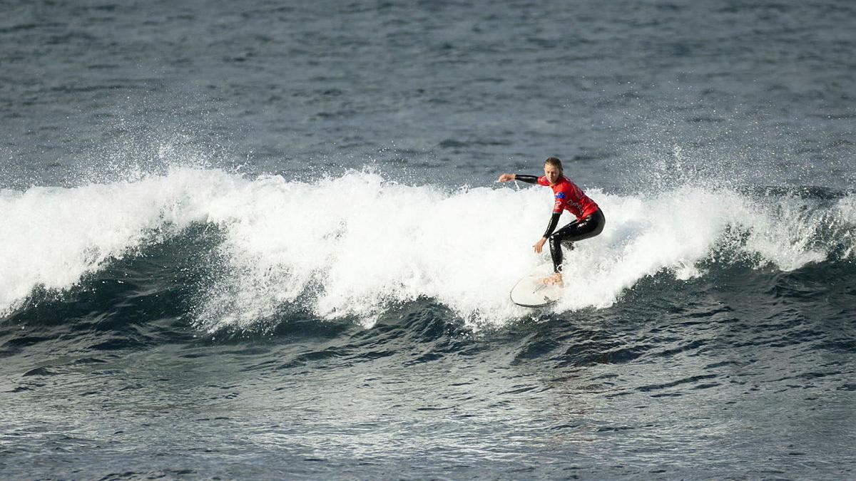 A person in a red rash shirt surfing a wave.