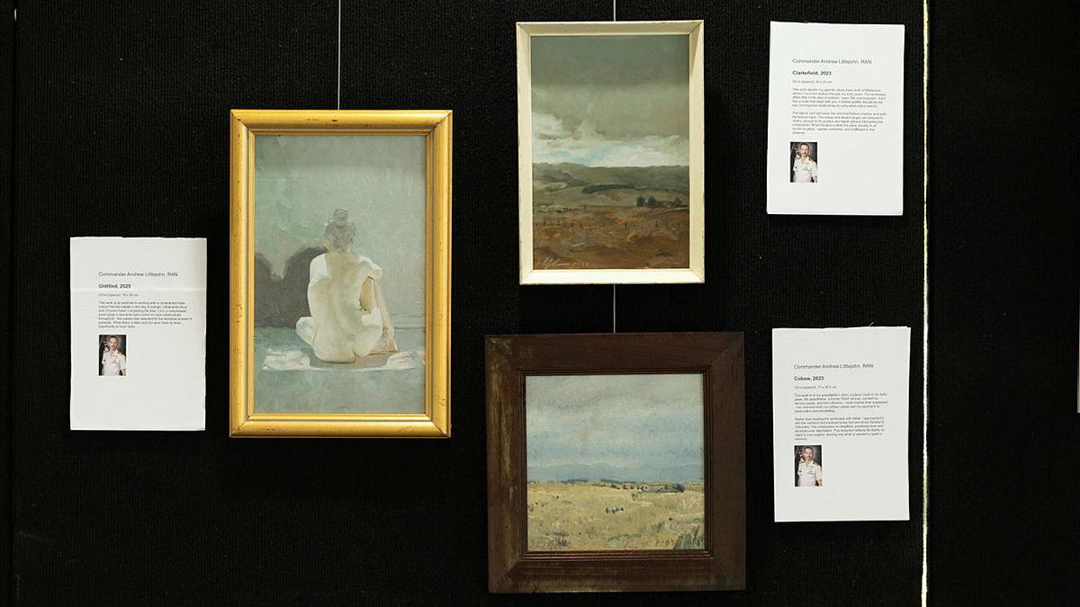 Oil paintings hang on a black wall.