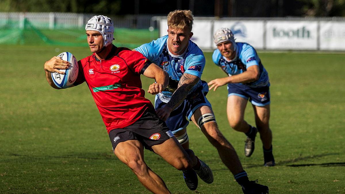 Three men play a game of rugby.