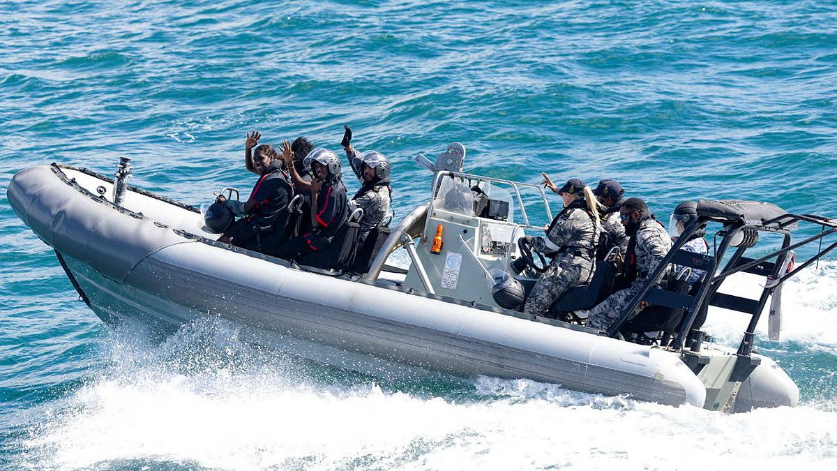 People wave from a boat at sea.