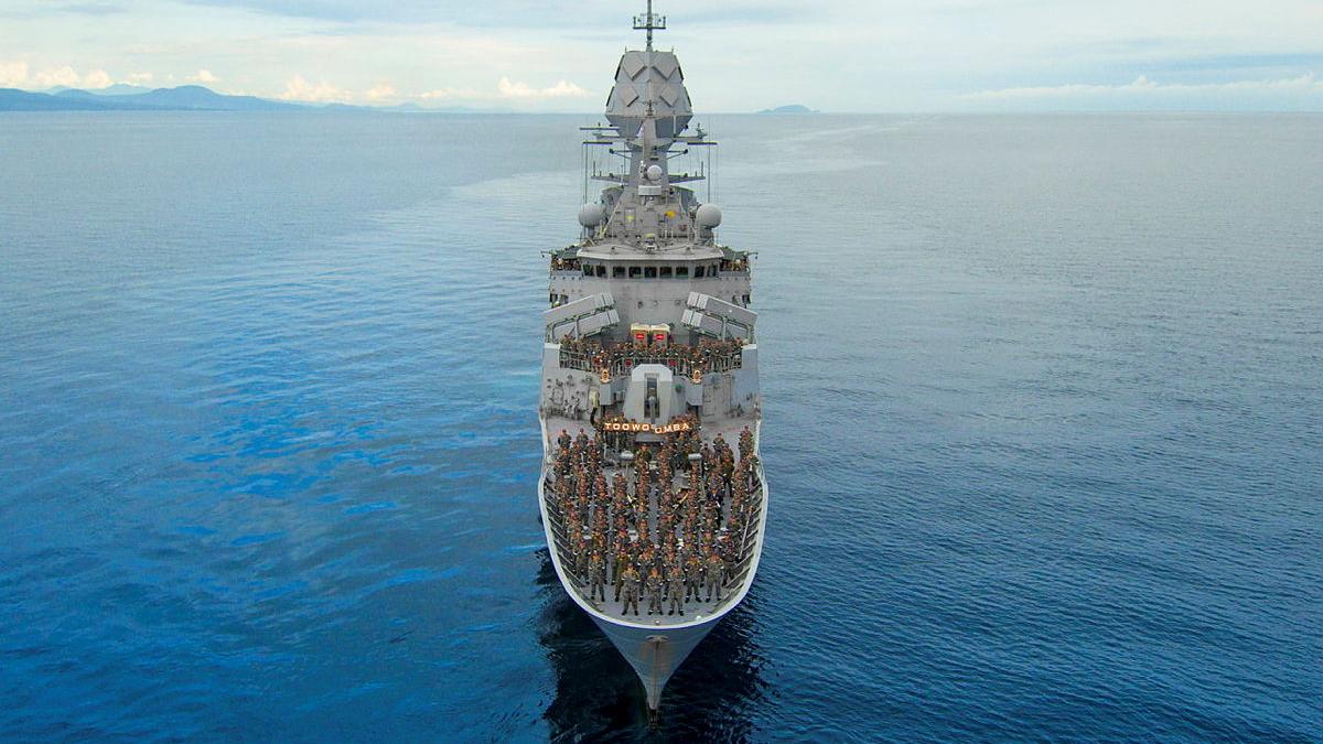 The crew of a ship pose for a group photo on the deck.