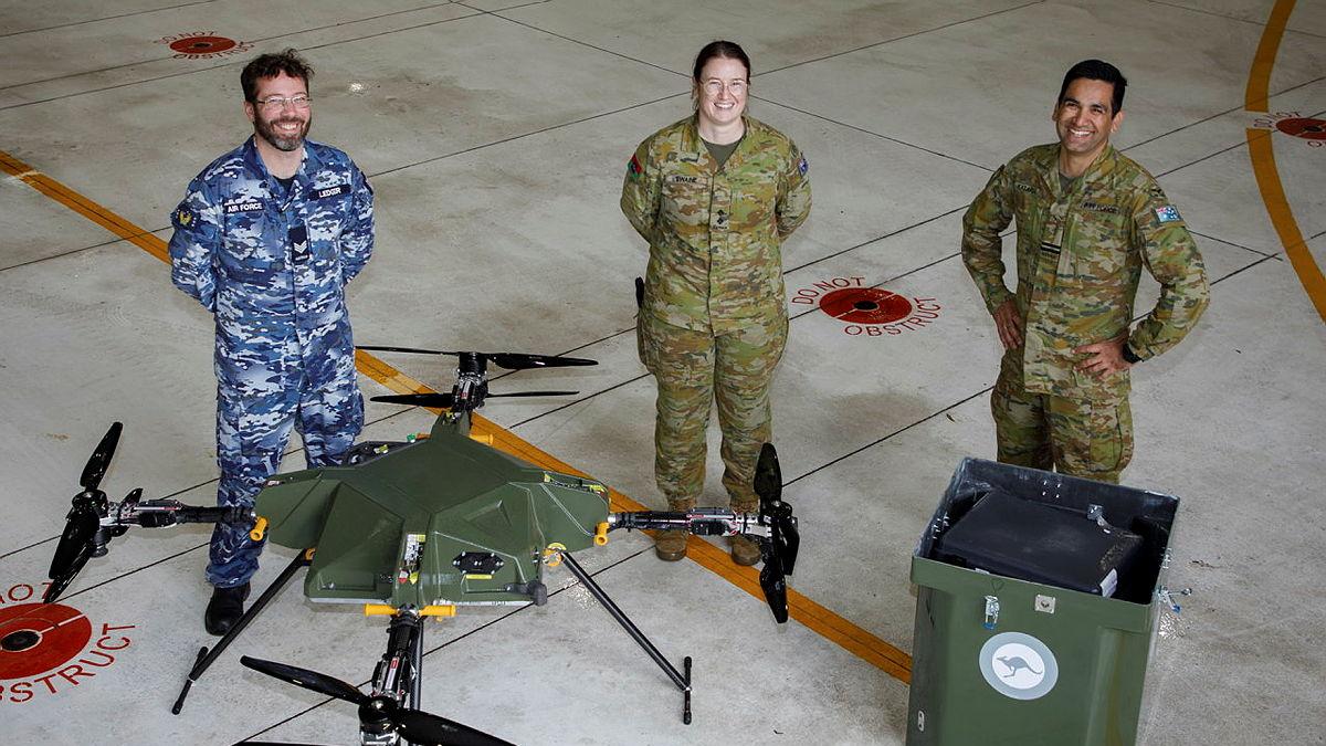 Three people in military uniform standing with a drone. 