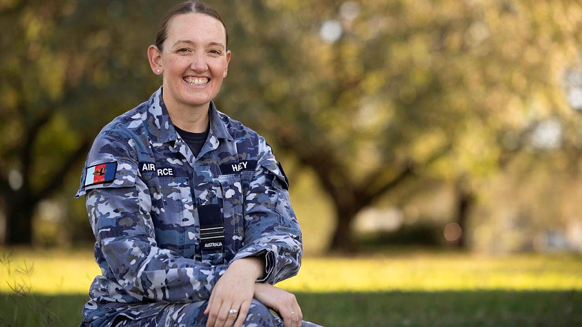 A woman in Air Force uniform sitting down smiling at the camera.