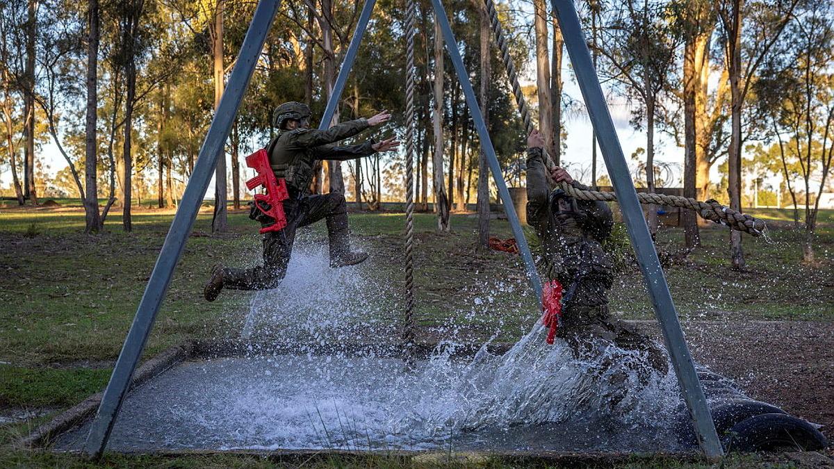 Australian Army trainees from the School of Infantry take a leap of faith over a water obstacle during Exercise HardCorps to complete their Riflemen's course at Singleton Military Area, NSW.
