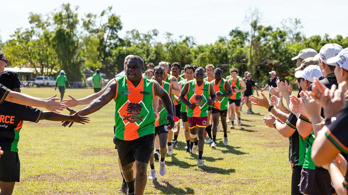 A sports team runs out onto the field and high fives spectators. 