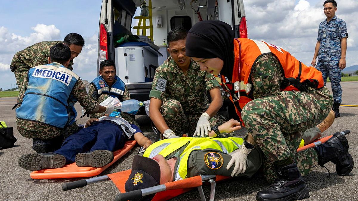 Malaysian army medics assist a simulated injured aviator on a stretcher.