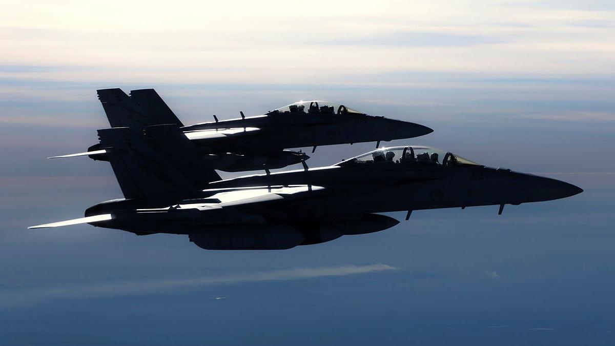 Two jets flying side by side in the sky.