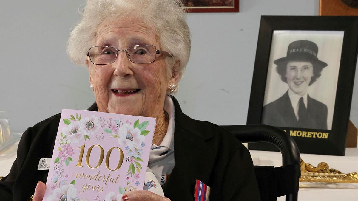 A woman holds up a 100th birthday card.