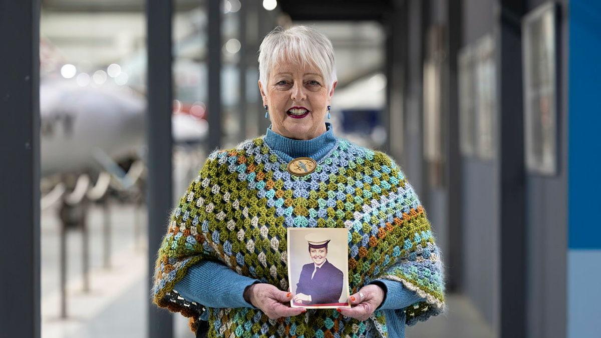 A woman holding an historical portrait image of herself.