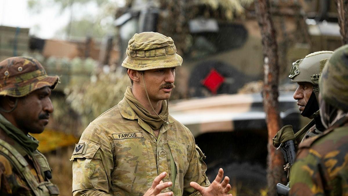 Australian Army soldier Private Harrison Fawcus from the 3rd Battalion, The Royal Australian Regiment, talks to Papua New Guinea Defence Force soldiers during Exercise Southern Jackaroo at Townsville Field Training Area, Queensland.