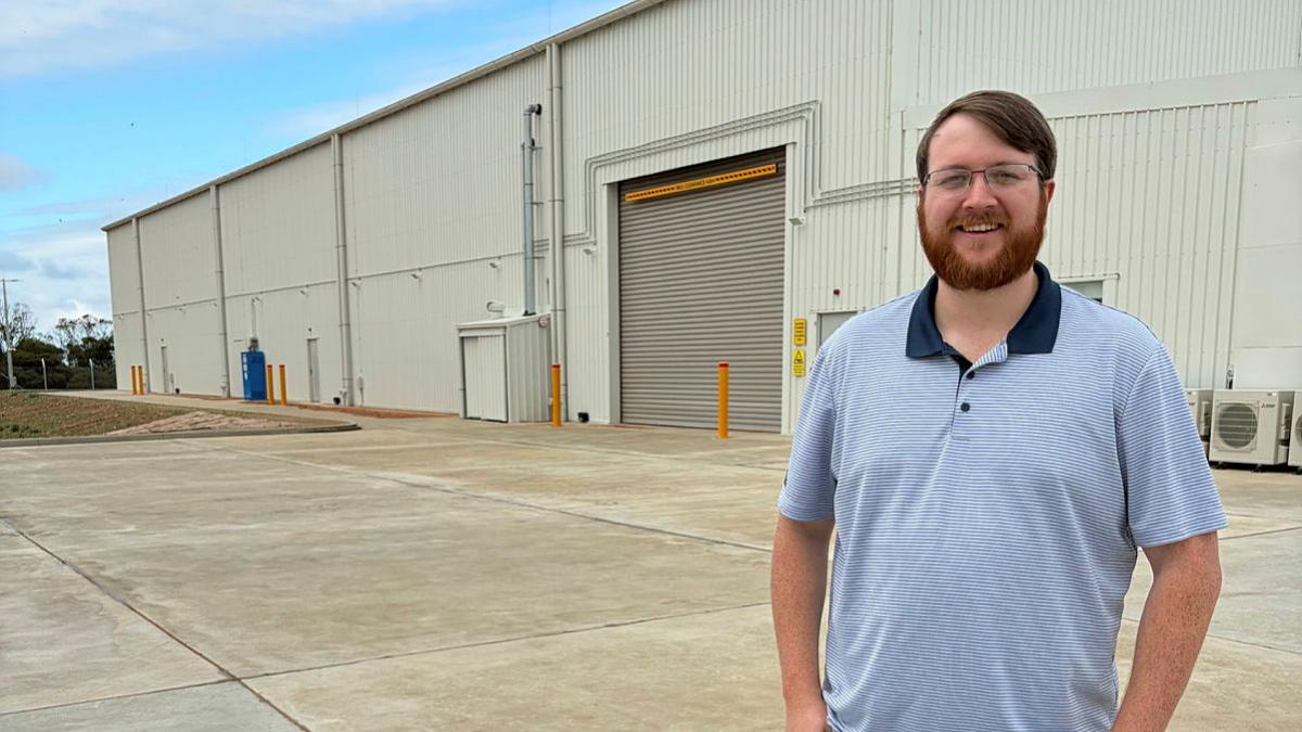 A man in civilian clothes stands outside a warehouse.