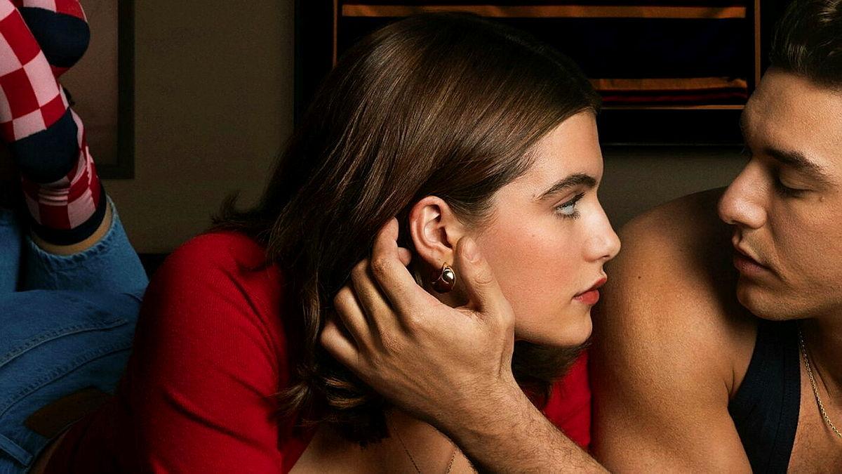 A young woman and a young man look into each other's eyes as he touches her cheek.