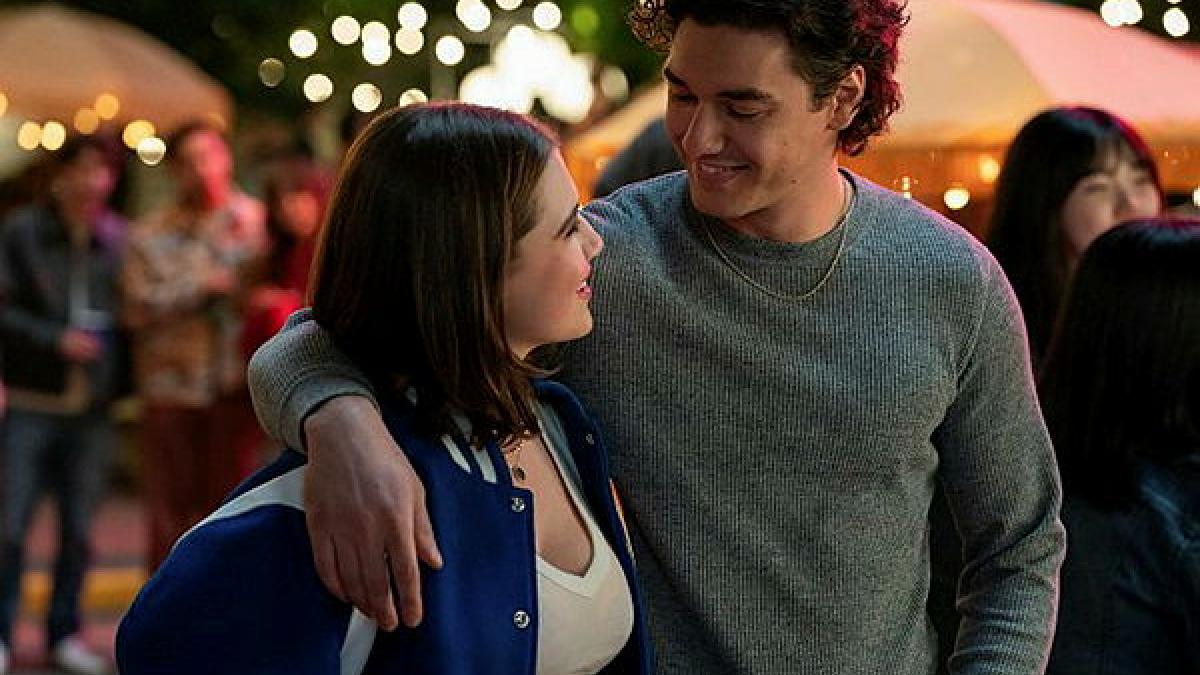 A young man and woman put an arm around each other and look into each other's eyes.