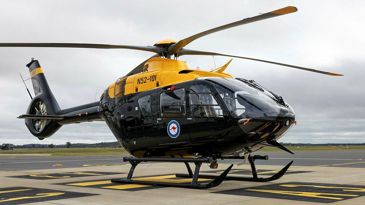 A yellow and black helicopter on the tarmac.