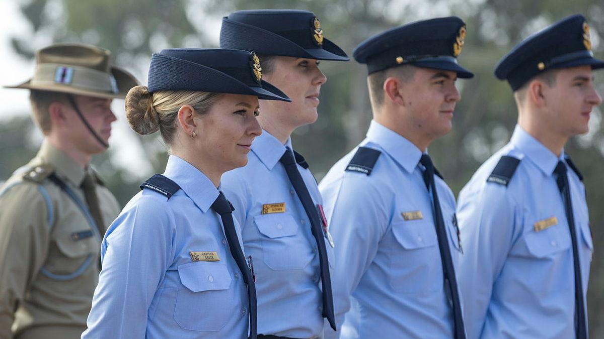 Five military members stand at attention. 