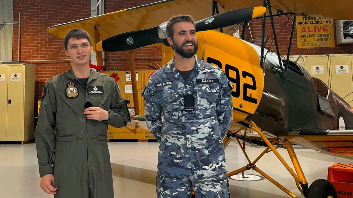 Two Air Force officers stand in front of a light plane.