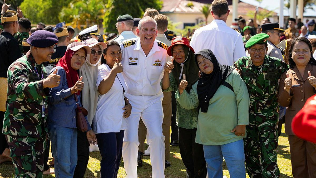 A Navy member poses for a photo with Indonesian locals.