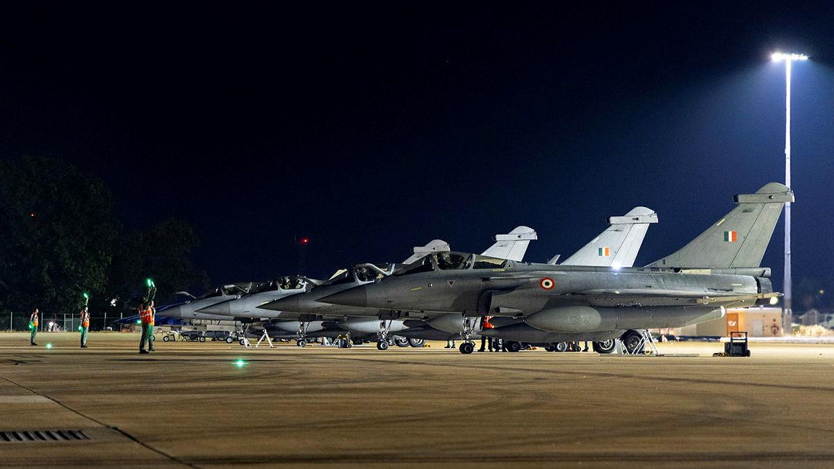 Jet aircraft lined up on the tarmac at night preparing for takeoff.