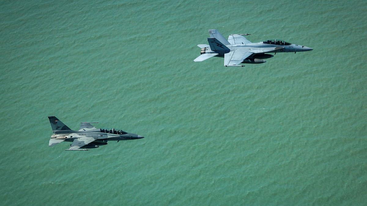 Two aircraft fly over a body of water.