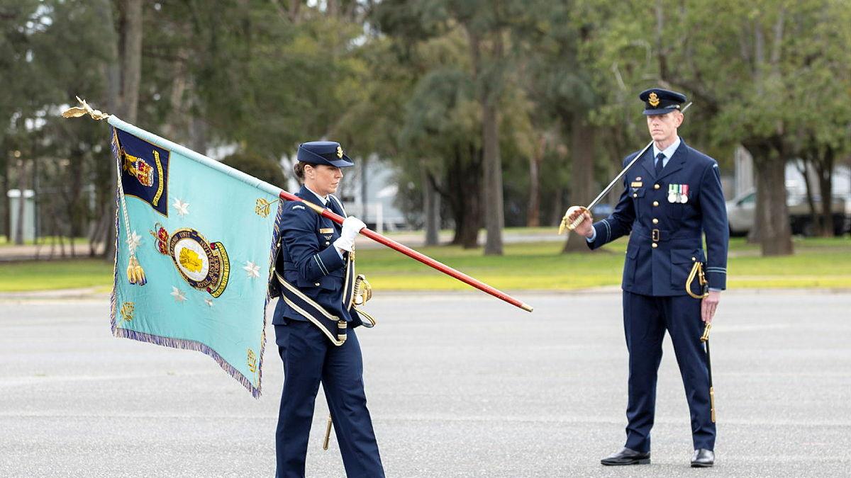 Two military personnel, one with a flag and the other with a sword.