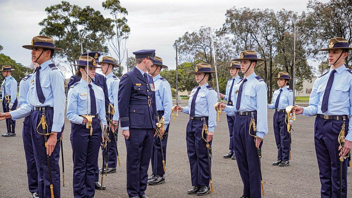 An Air Force leader inspects a row of cadets who stand on parade.