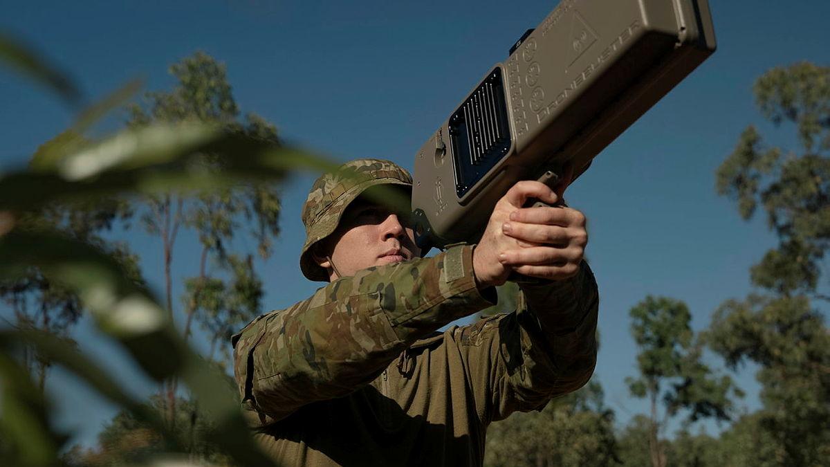 An Australia soldier launches a drone into the air.