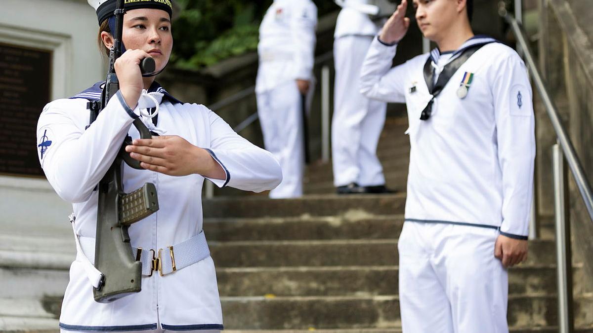 Sailors stand to attention on the staircase.