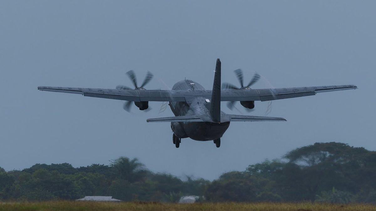 An aircraft flies off into an overcast sky.