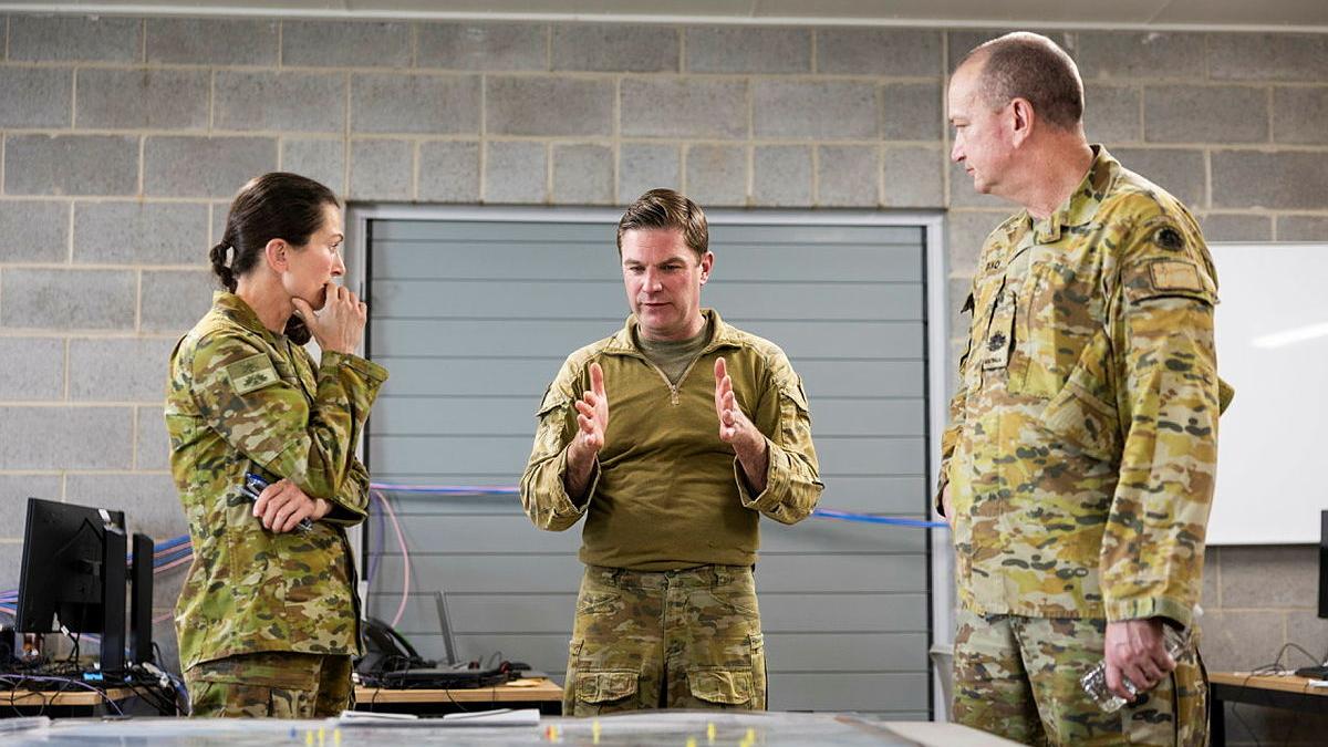 Three people in uniform speaking indoors.