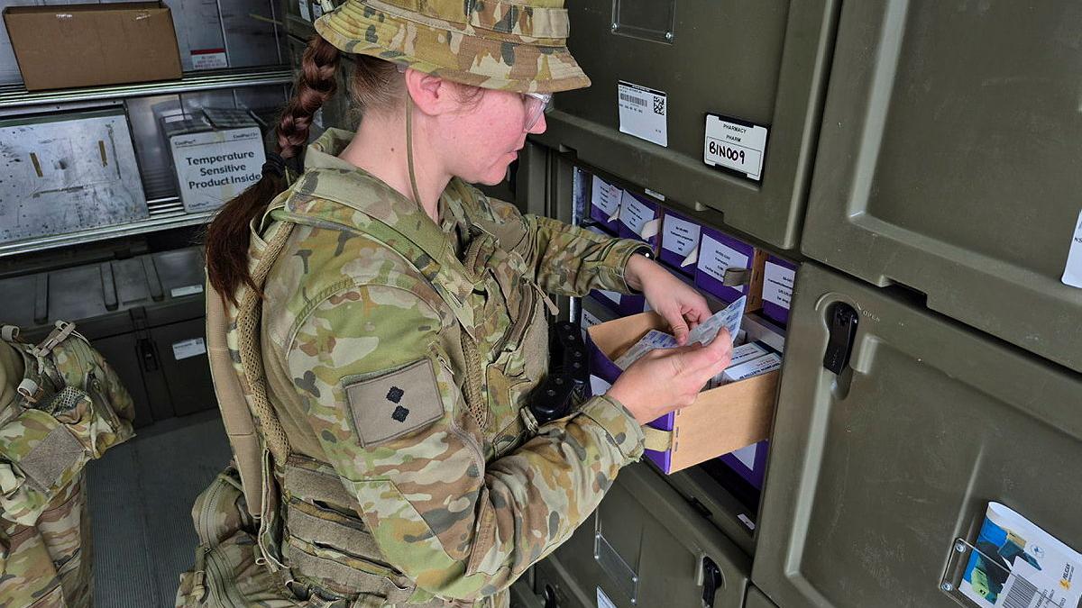 An Army member opens a box to retrieve an item with a label on.