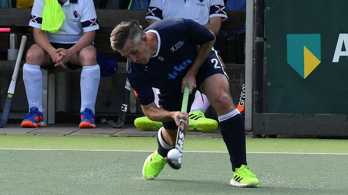 A man strikes a hocket ball on the field during a game.