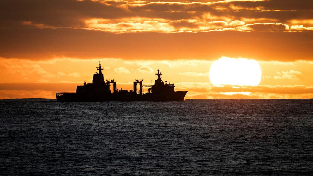 A ship's silhouette is seen against a yellow sky and sun.