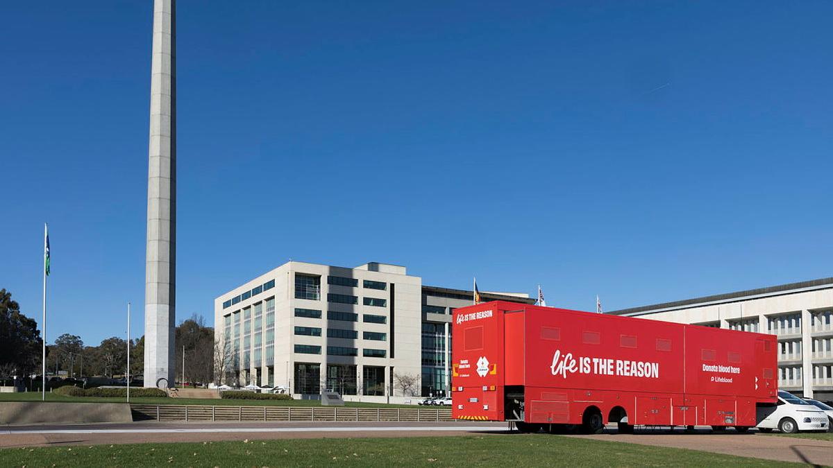 A red van with the text 'Life is the reason', next to buildings and an eagle statue.