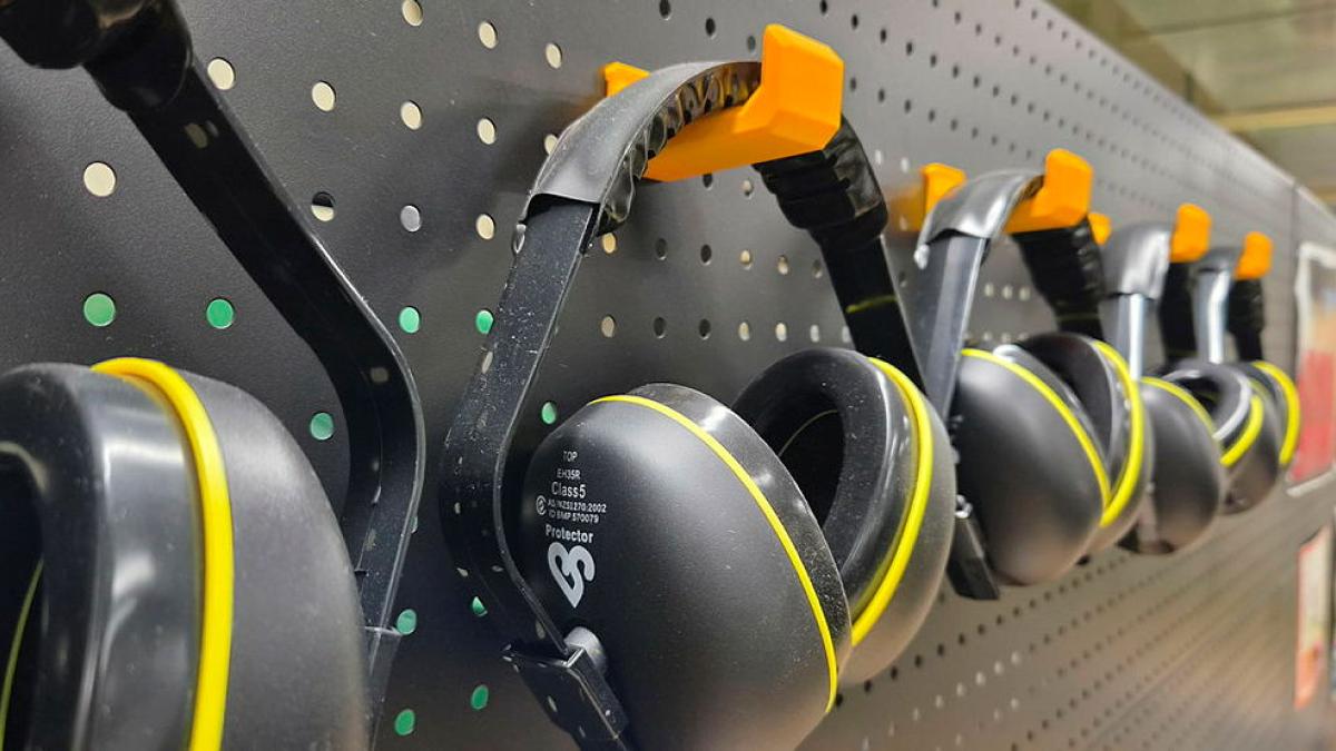 A pegboard rack holds a collection of black and yellow headphones.