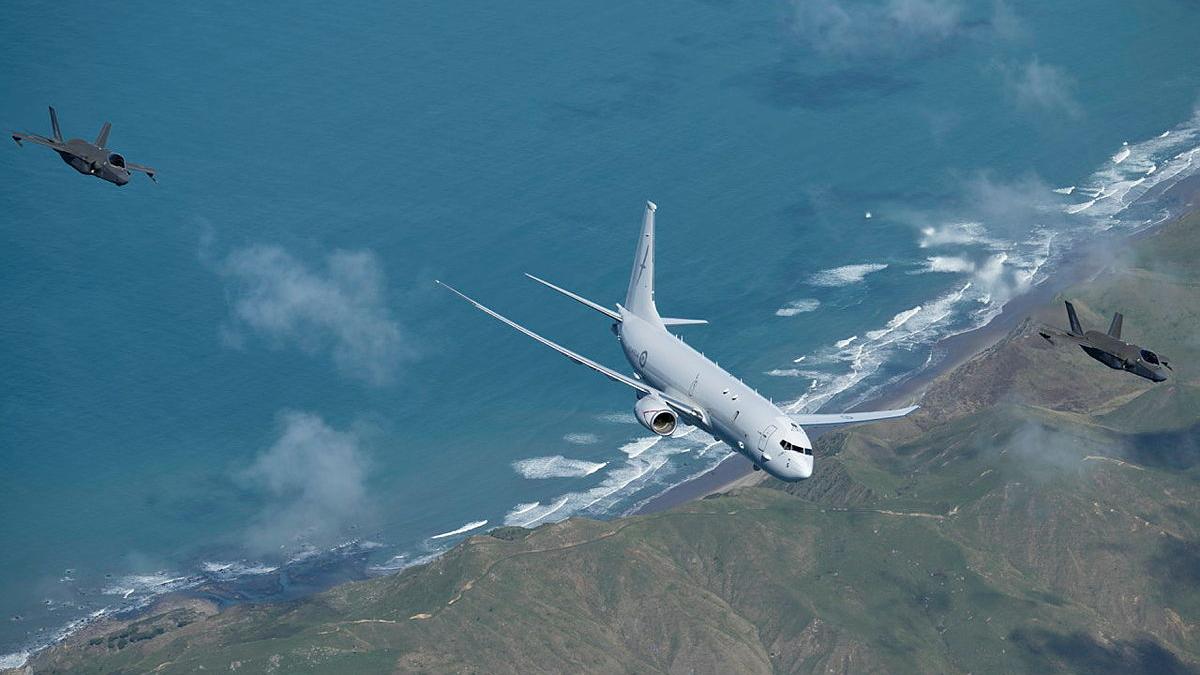Three aircraft fly over a shoreline.