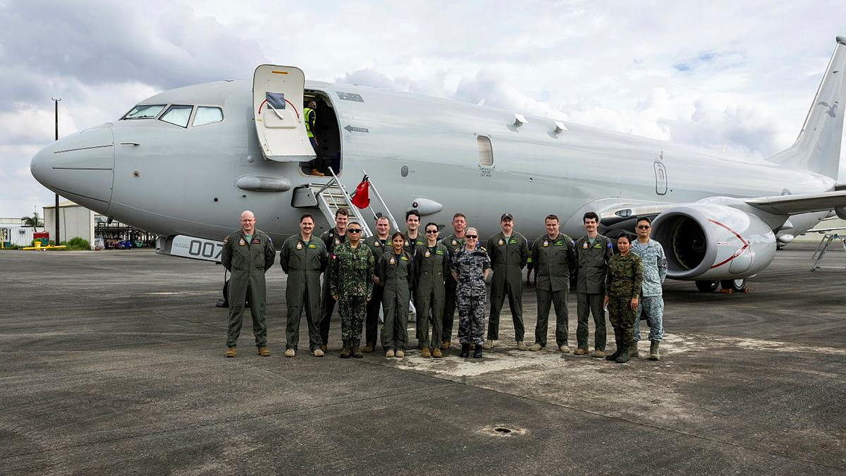 A group of Australian and Philippino Air Force personnel stand in front of a Poseidon P-8A aircraft.