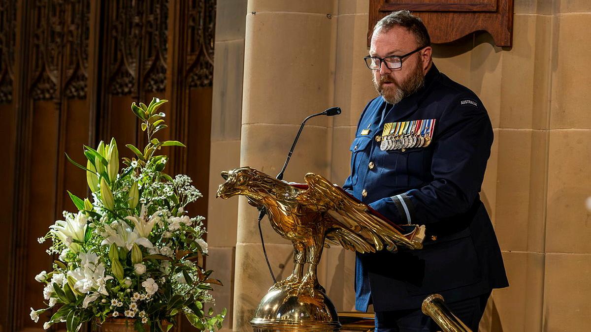 A military member reads at a lectern shaped like a gold eagle.