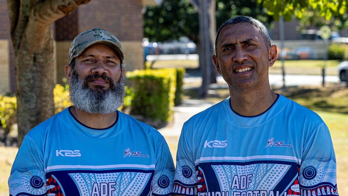 Two brothers face the camera dressed in colourful Australian Defence Force touch football shirts.