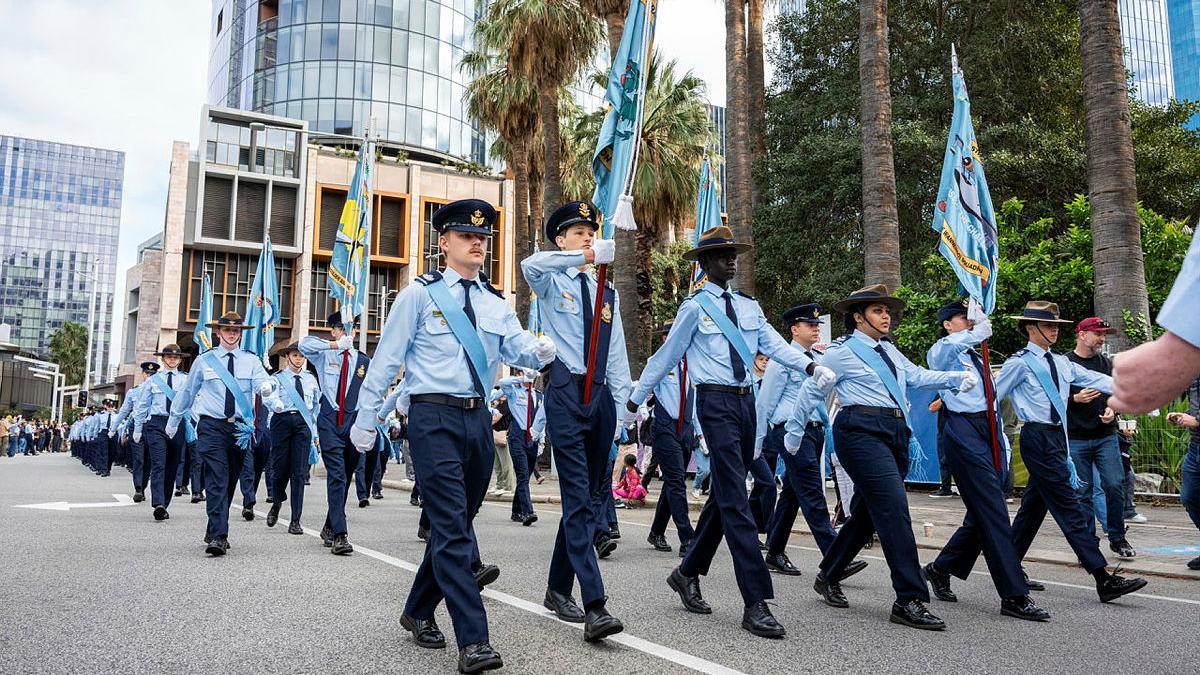 A large formation of young military personnel march through a city.