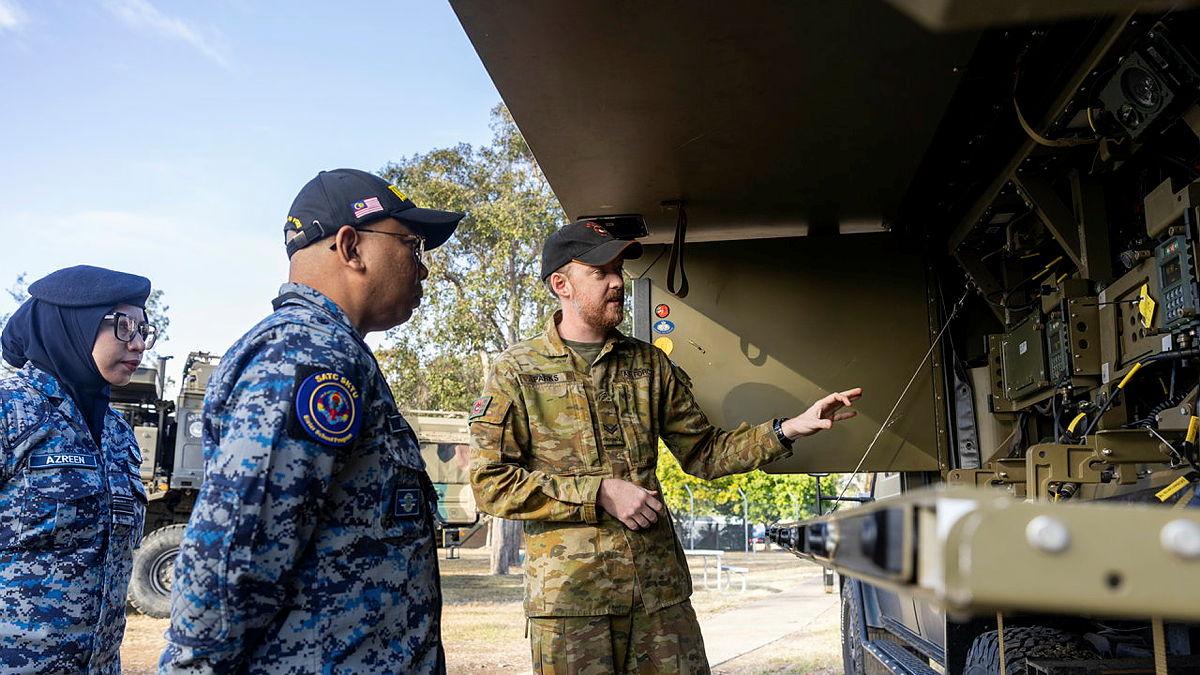 An Air Force leader points two Malaysia Air Force personnel towards a truck.
