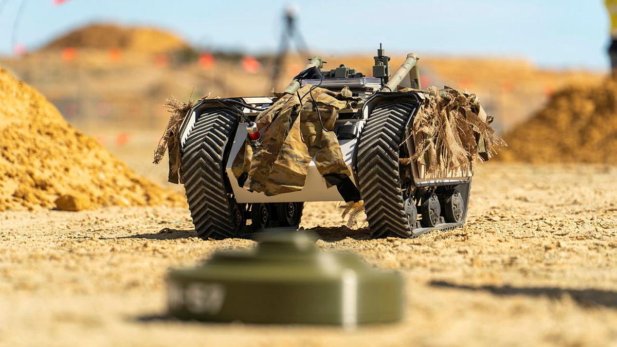 An uncrewed ground vehicle driving over a dirt road.