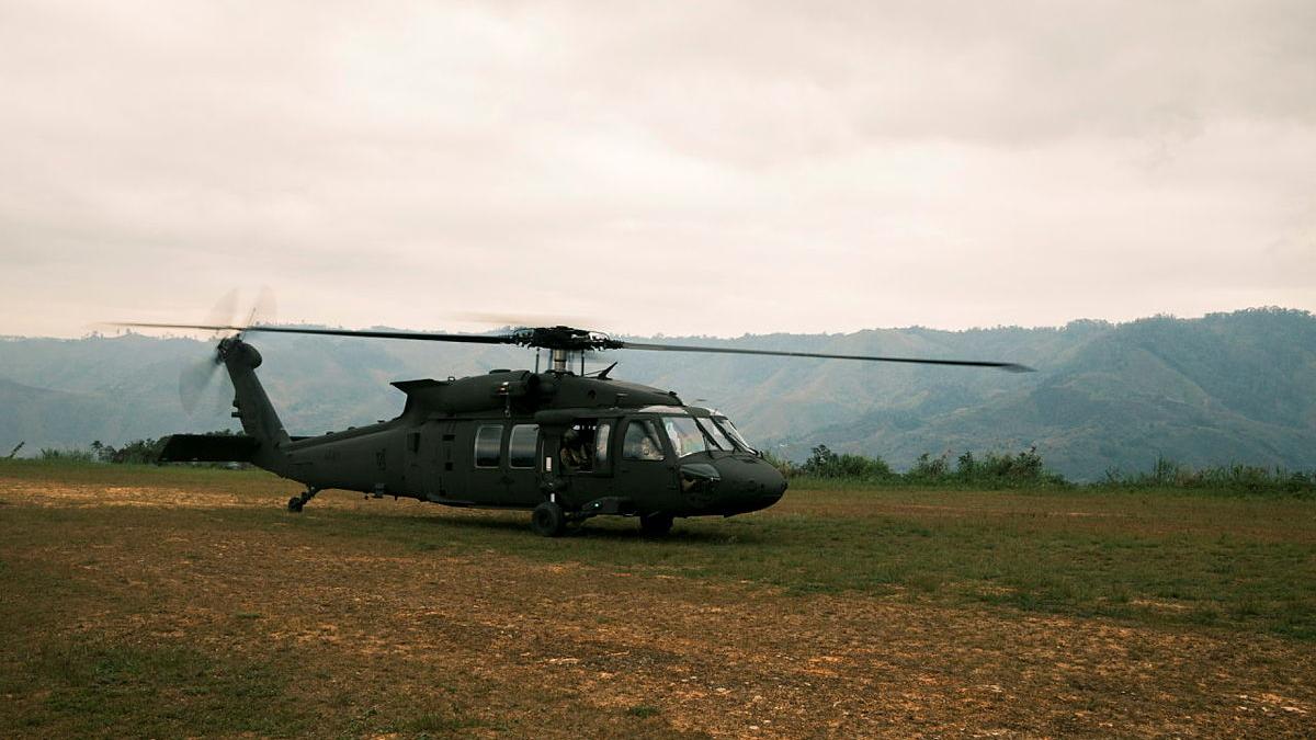 A helicopter on a stretch of grass in a mountainous region.
