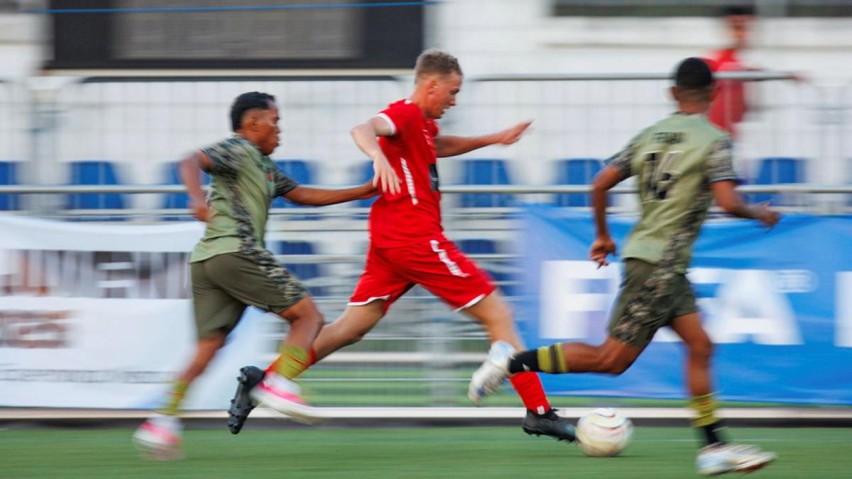 Three men compete for a soccer ball during a game.