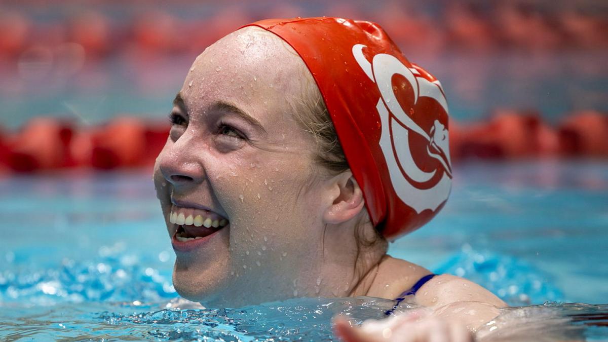 A smiling woman swims in a pool.