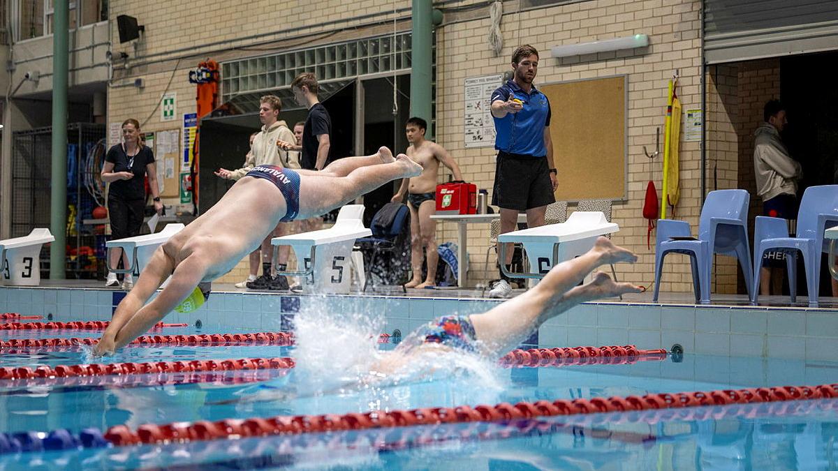 Two men dive into a swimming pool.