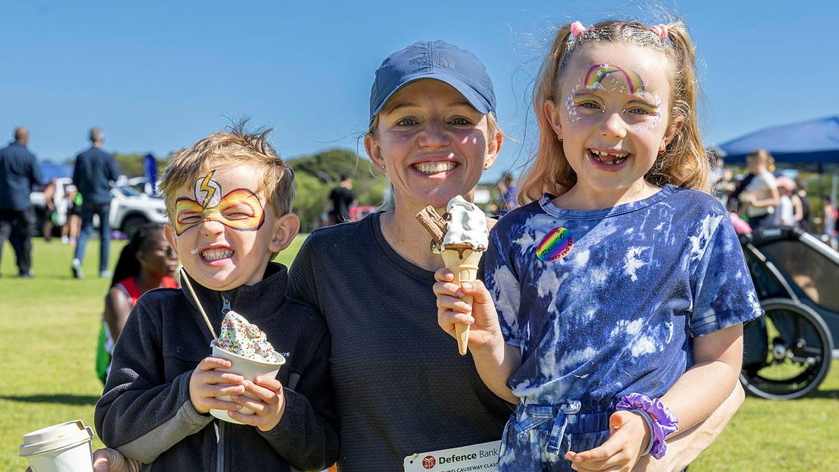 A mum hugs her young son and daughter, who both hold ice creams.